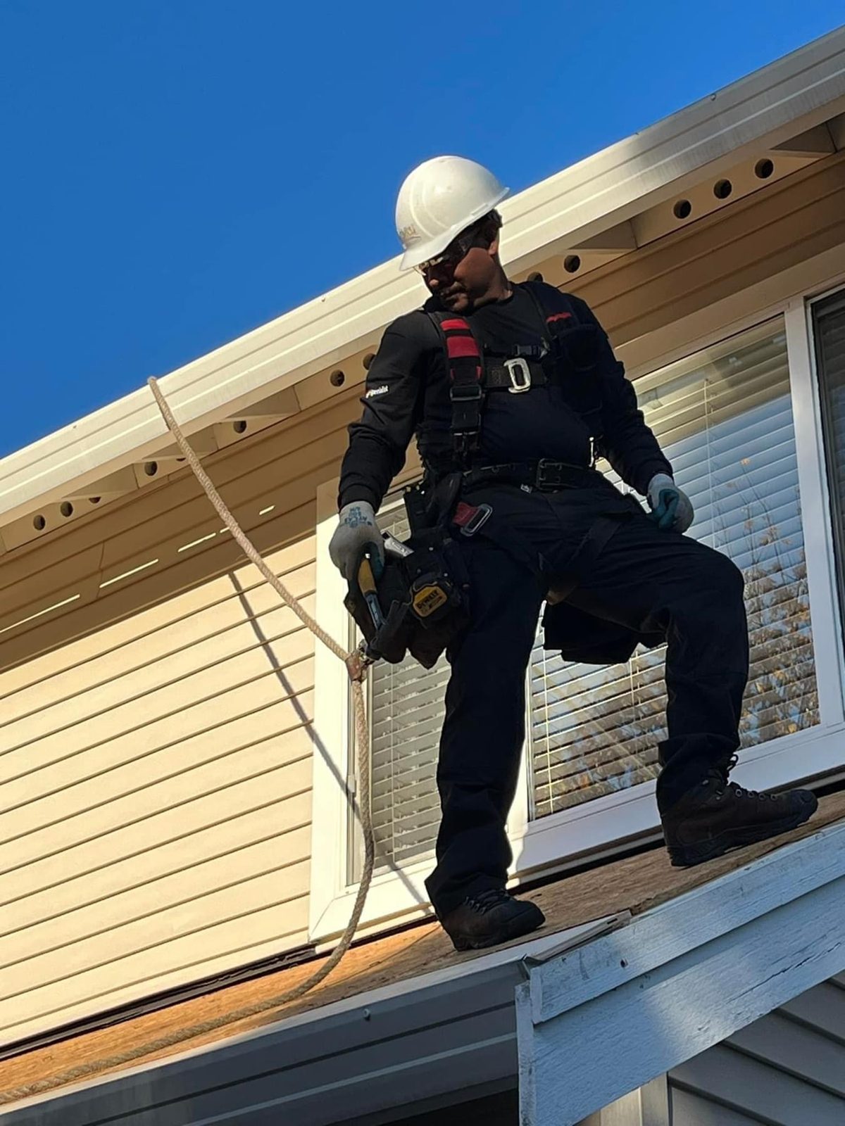 High Standards roofer in full safety harness and hard hat working a roof edge
